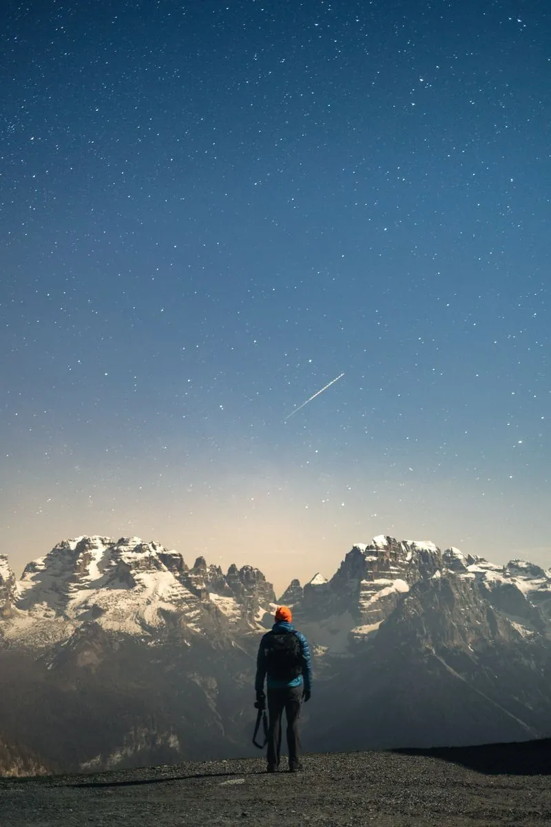 Person looking toward mountains under a starry sky